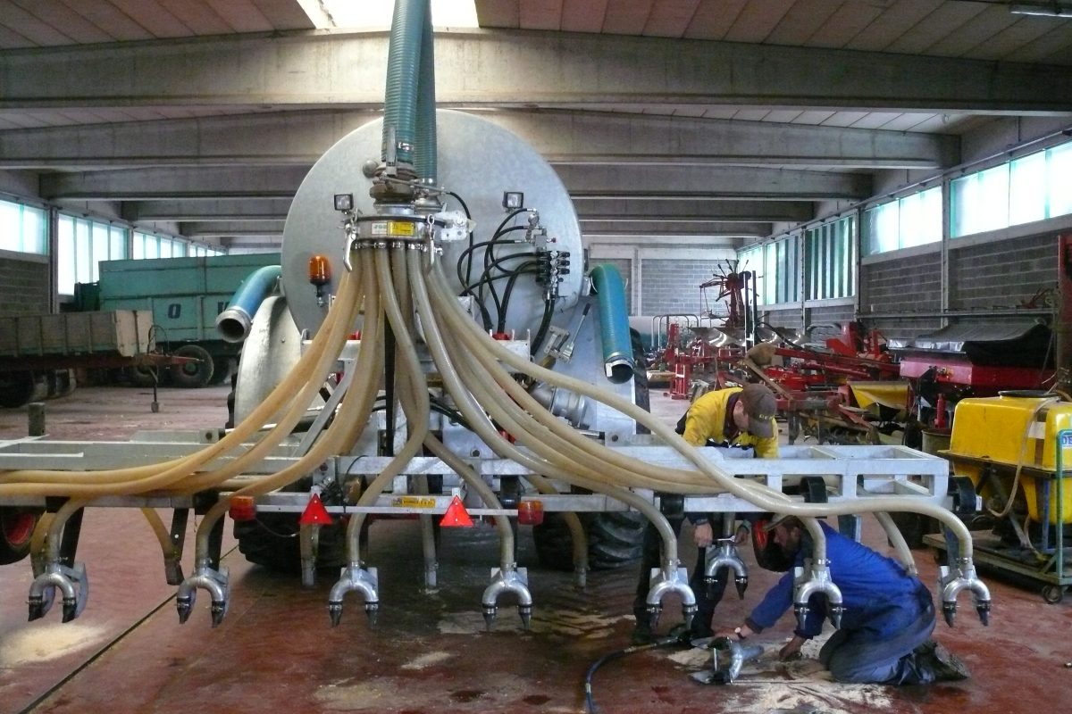 Twee landbouwers werken aan een mesttank