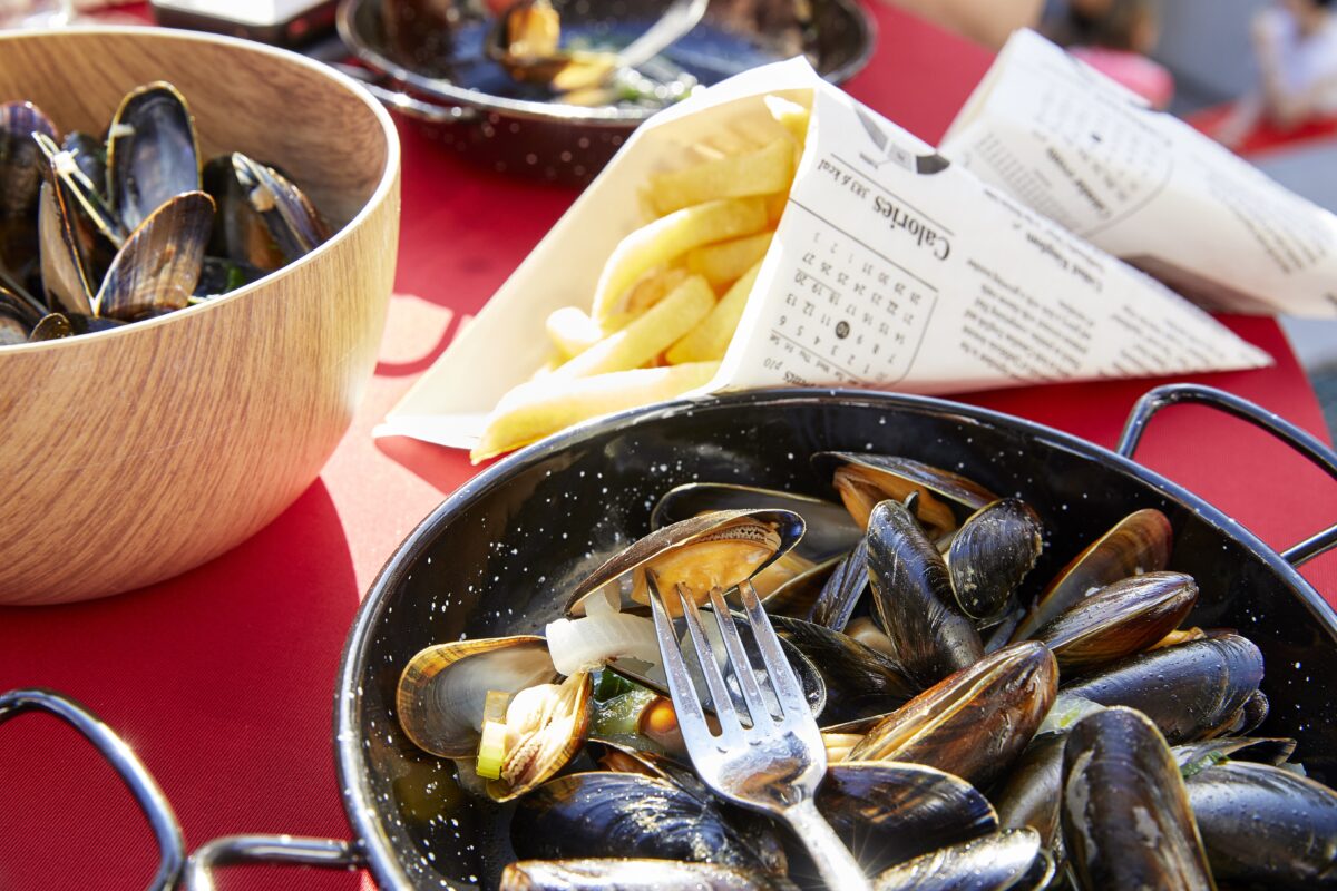 Schaaltje met klaargemaakte belgische mosselen uit maricultuur, met daarnaast een puntzak met frietjes