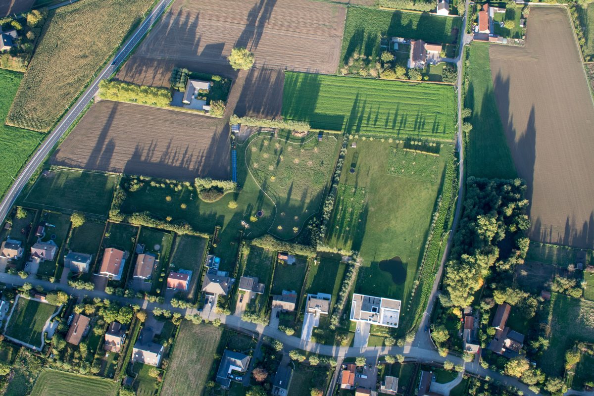 Luchtfoto van een Vlaamse lintbebouwing met huizen en erachter tuinen die het achterliggende landschap afsnijden en afboorden
