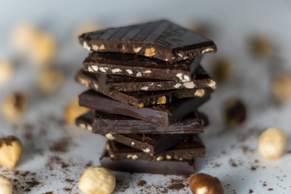 Pieces of dark chocolate with chopped nuts surrounded by entire hazelnuts