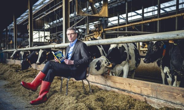 Joris Relaes met boek in de ILVO melkveestal