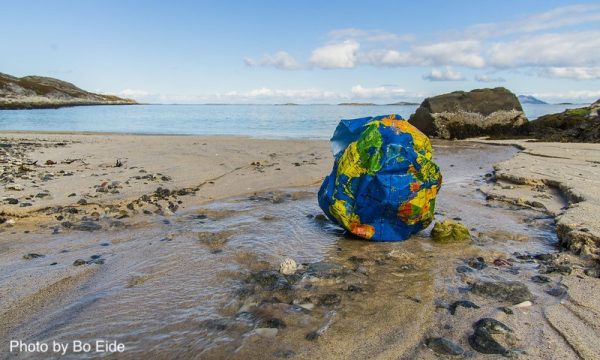plastic crumpled up globe on beach