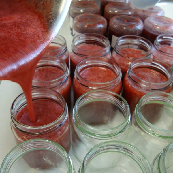 filling pots with red colored jam