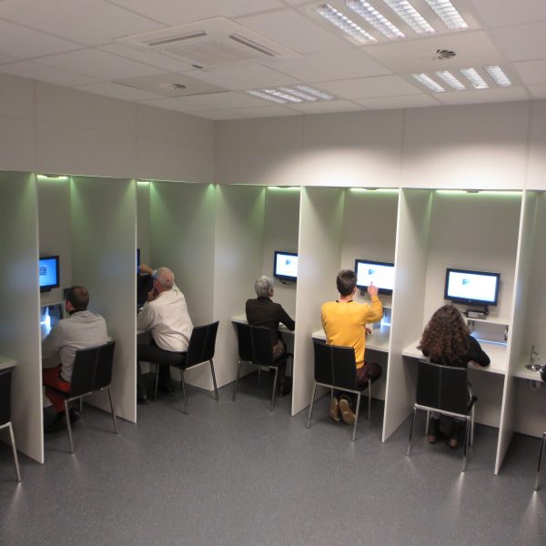 People sitting at cubicles with computer screens
