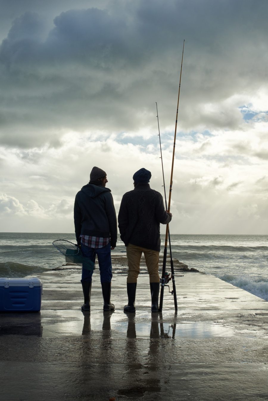 2 vissers op het strand, ze lezen modebladen, ze kijken in het rond, ze dromen van een vis