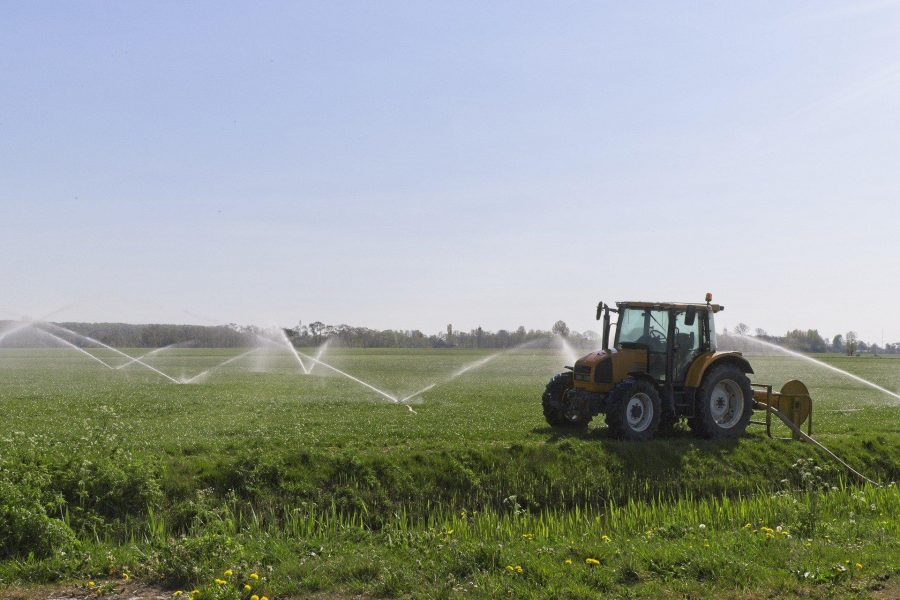 foto van sproeiers in een veld, met een tractor op de voorgrond