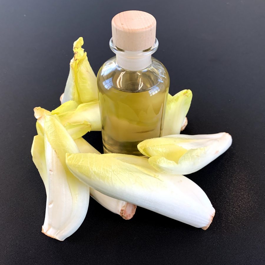 Belgian endive leaves and a glass bottle with light yellow liquid